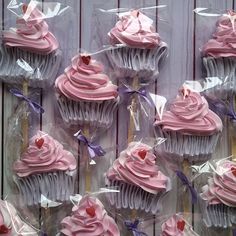 cupcakes with pink frosting and hearts on sticks in plastic wrapper bags