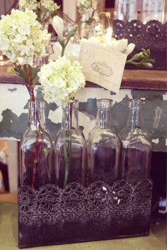 vases with flowers in them are sitting on a shelf next to an empty bottle