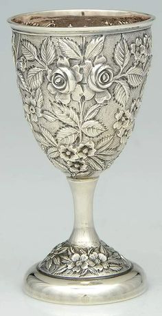 an ornate silver goblet with flowers and leaves