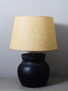 a black table lamp with a yellow shade on the top and bottom, against a white wall