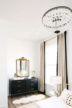 a bedroom with a chandelier hanging from the ceiling and a bed in front of a window