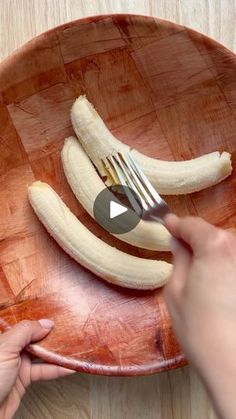 someone is cutting bananas on a wooden plate with a knife and fork in the middle