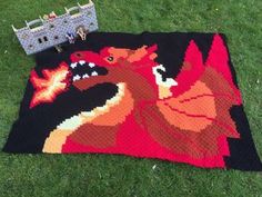 a crocheted blanket with an image of a dragon on it and a toy castle in the background