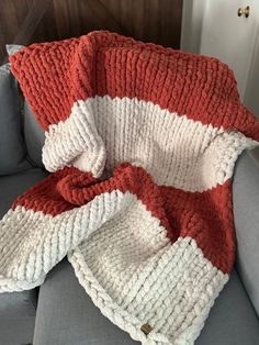 a red and white knitted blanket sitting on top of a couch