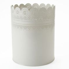 a white candle holder with lace trimmings on the edges and sides, against a white background