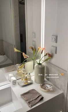 a bathroom with a sink, mirror and flowers in the vase on the counter top