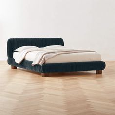 a bed sitting on top of a hard wood floor next to a white wall and wooden floors