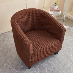 a brown chair sitting on top of a floor next to a glass table