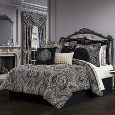 a bed with black and white comforters in front of a fireplace