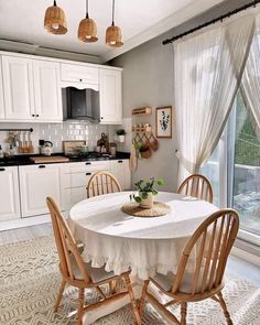 a white table and chairs in a kitchen next to an open window with sheer curtains