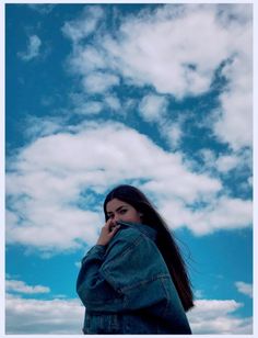 a woman standing in front of a cloudy blue sky