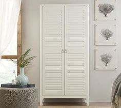 a large white closet in a bedroom next to a bed and window with pictures on the wall