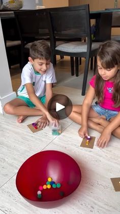 two young children sitting on the floor playing with magnets and paper balls in front of them