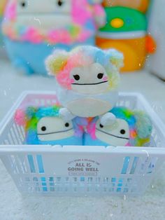 two stuffed animals in a plastic basket on the floor with other toys behind them,