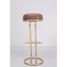 a gold metal stool with a brown leather seat and foot rests on a white background