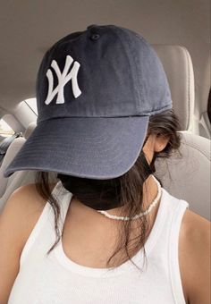 a woman wearing a new york yankees hat in the back seat of a car,