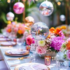 a table set for a party with disco ball centerpieces and flowers on it