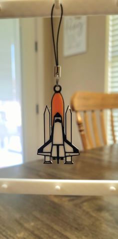 an ornament shaped like a space shuttle hanging from a string on a table