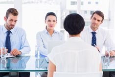 three business people sitting at a table having a meeting with one man in the middle