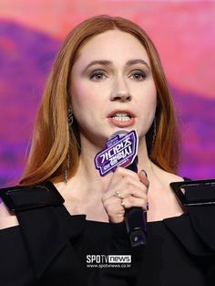 a woman with red hair is holding a microphone