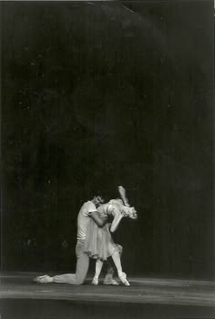 two ballet dancers in the middle of a dance pose, one holding the other's leg