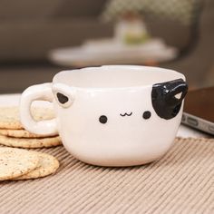 a coffee cup with a cow face on it next to crackers