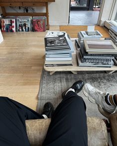 a man sitting on a chair in front of a table filled with books and magazines