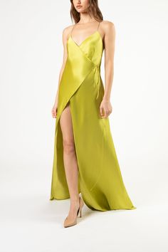 a woman wearing a lime green dress with a slited skirt and high heel shoes