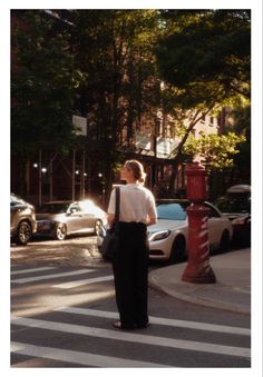 a woman standing on the side of a street next to a red fire hydrant