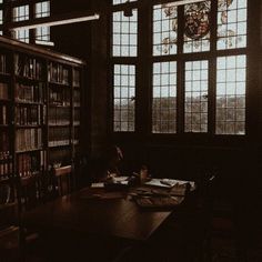 a dark room with lots of books on the shelves and two people sitting at a table in front of them