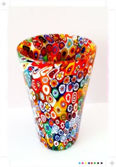 a colorful glass vase sitting on top of a white table