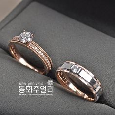 two gold wedding rings with diamonds sitting on top of a black cloth covered seat in a showroom