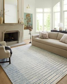 a living room filled with furniture and a large rug on the floor in front of a fire place