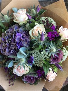 a bouquet of flowers sitting on top of a piece of brown paper with purple and white flowers