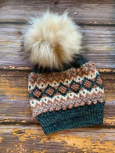 a knitted hat with a pom - pom sitting on top of it