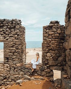 a woman is standing in an old ruin by the beach looking out at the ocean