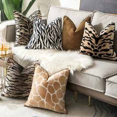 a white couch topped with lots of pillows and giraffe print pillow cases on top of it