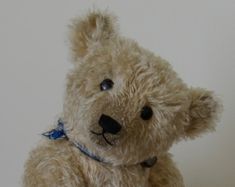 a brown teddy bear sitting on top of a wooden table next to a white wall