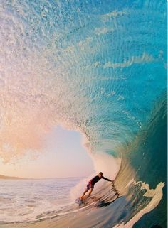 a man riding a wave on top of a surfboard in the ocean under a blue sky