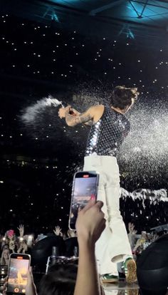 a man is jumping in the air with his cell phone while people are watching him