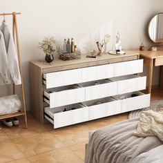 a white dresser sitting next to a bed in a bedroom on top of a hard wood floor