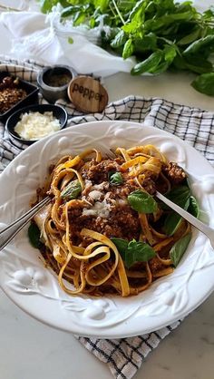 a white bowl filled with pasta and meat sauce on top of a table next to other dishes