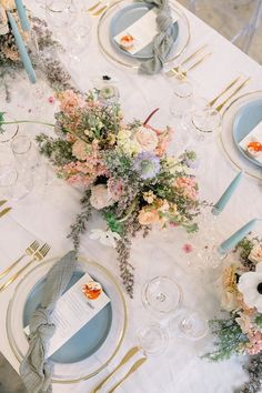 the table is set with blue and white plates, silverware, and floral centerpieces