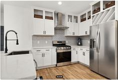 a kitchen with white cabinets, stainless steel appliances and wood flooring is pictured in this image