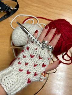 a woman's hand holding a pair of scissors next to a ball of yarn