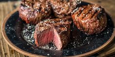 steaks on a plate with salt and pepper sprinkled on the top, ready to be eaten