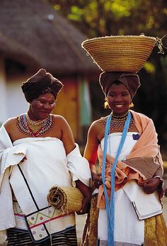 two women in traditional african garb standing next to each other with baskets on their heads