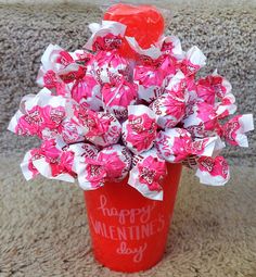 a valentine's day candy bouquet in a red cup on the floor with happy valentine's day written on it