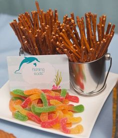 there is a plate full of gummy bears next to a bucket of pretzels