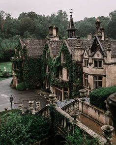 an old house with ivy growing all over it's walls and roof, surrounded by greenery